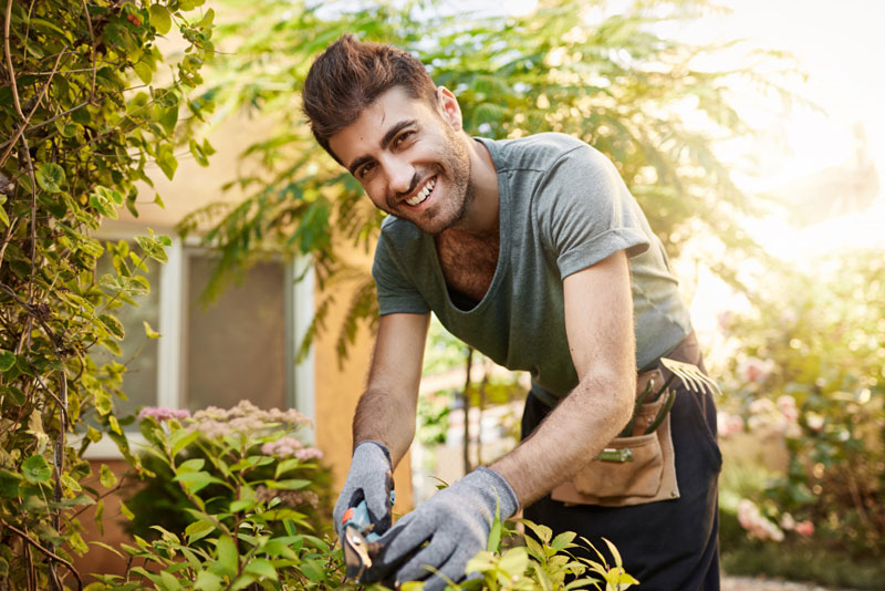 close-up-outdoors-portrait-beautiful-cheerful-bearded-caucasian-farmer-blue-shirt-gloves-smiling-working-with-garden-tools-his-farm-near-countryside-house